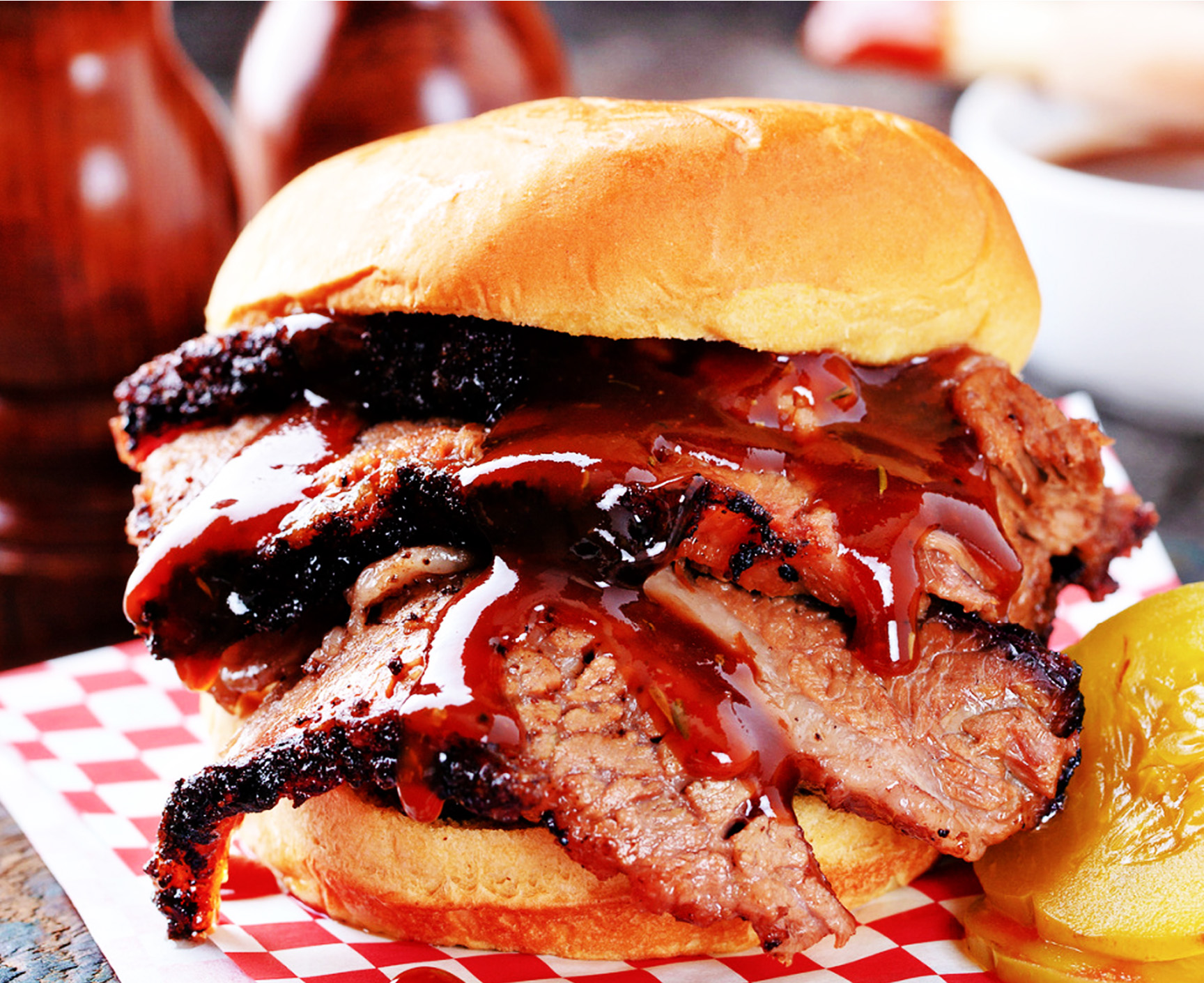 Sliced brisket sandwich with BBQ sauce and pickles